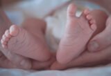 The Tiny Feet Of A Newborn Baby In Mother's Hands