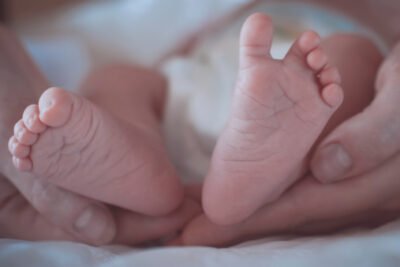 The Tiny Feet Of A Newborn Baby In Mother's Hands